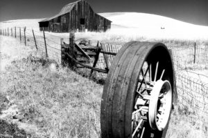 A barn and metal tractor wheel near Goldendale, Washington by Gary Quay