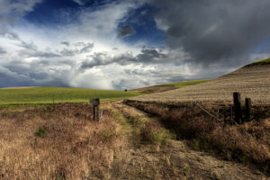 A farm lane in Eastern Oregon with dramatic storm clouds by Gary Quay
